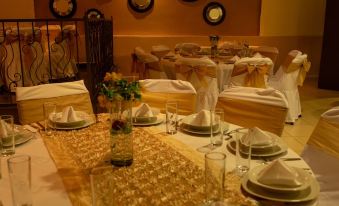 a well - decorated dining room with multiple tables set for a formal dinner , complete with gold tablecloths , wine glasses , and nap at Hotel St. George