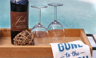 a wooden tray with two wine glasses and a bottle of wine on a table near a pool at The Lighthouse