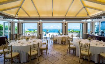 a large dining room with tables and chairs set up for a formal event , overlooking the ocean at Condado Vanderbilt Hotel