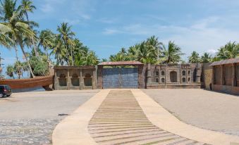 There is a walkway flanked by palm trees and buildings on both sides, leading to the beach at Seagate Hotel