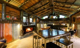 a modern wooden interior with a tiled floor and metal roof , featuring a dining table , bar stools , and a fireplace at Marsden Lake Resort Central Otago