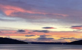 a beautiful sunset over a large body of water , with a boat visible in the distance at Lodges on Vashon