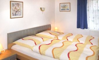 a bed with a yellow and white striped blanket is in a room with blue curtains at Paula