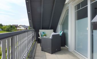 a balcony with a black railing , a white railing , and two black chairs on the balcony at Lona