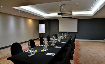 a conference room set up for a meeting , with multiple tables and chairs arranged in a semicircle at Fountains Hotel