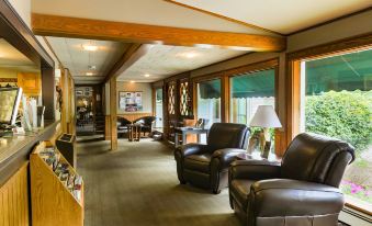 a spacious living room with leather furniture , including two couches and a chair , along with wooden beams on the ceiling at Woodwards White Mountain Resort, BW Signature Collection