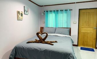 a bedroom with a large bed , blue curtains , and a heart - shaped decoration on the bed at Smile Resort