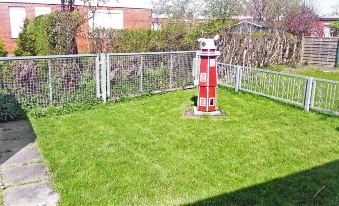 a red and white light house is sitting in a grassy yard surrounded by a fence at Gila