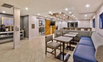 a modern hotel lobby with multiple seating areas , including couches and chairs , as well as a bar area at Staybridge Suites Pittsburgh Airport