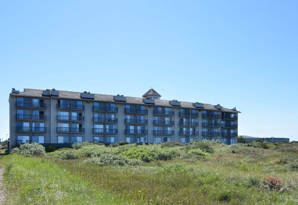 a large building with multiple balconies and a red roof is situated on a grassy area at Lighthouse Suites Inn