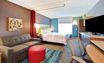 a modern hotel room with a bed , couch , and other furniture , as well as a living area with a couch and coffee table at Home2 Suites by Hilton Atlanta Marietta