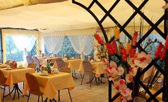 a well - decorated dining room with yellow tablecloths , chairs , and flowers on the tables , under a large white canopy at Antico Borgo Il Cardino