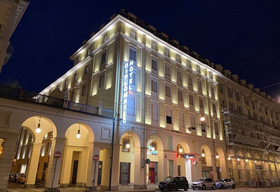 a large , white hotel building with a blue sign on the front is lit up at night at Hotel Diplomatic