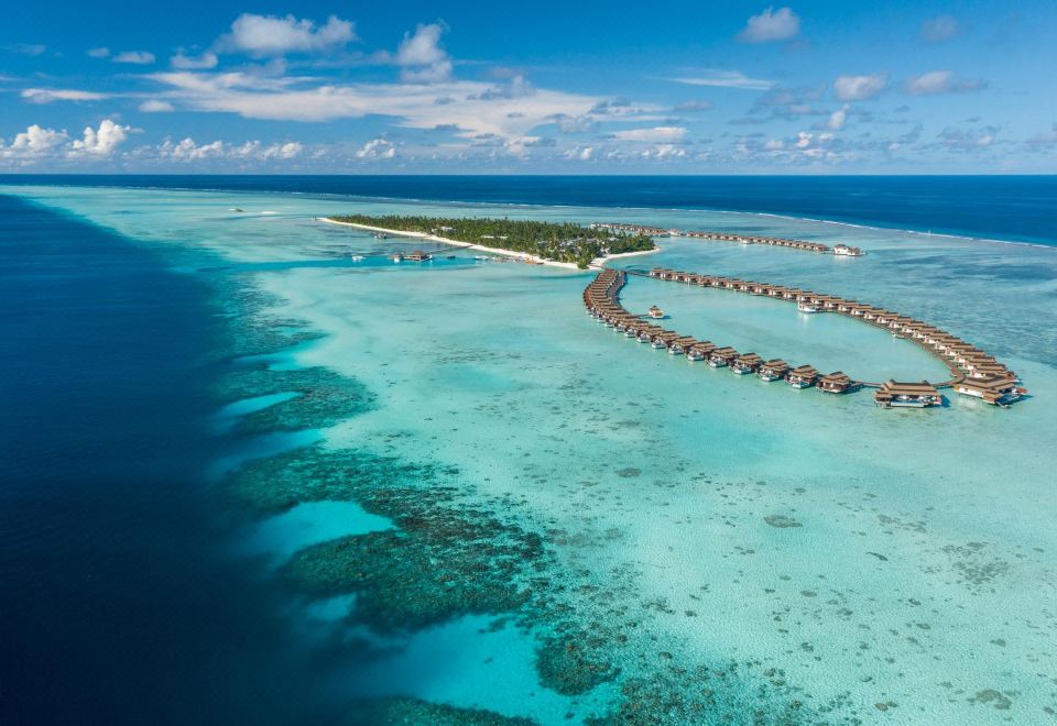 a luxurious resort is nestled on an island in the middle of clear blue water at Pullman Maldives All-Inclusive Resort