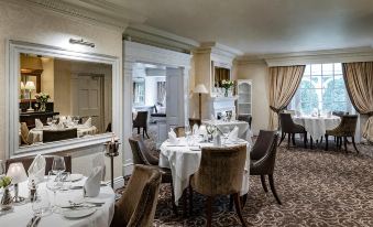 a large , elegant dining room with white tablecloths and elegant chairs set up for a formal dinner at Brandshatch Place & Spa