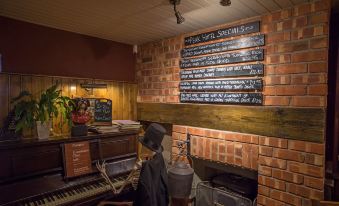 a man dressed in a top hat , standing in front of a brick fireplace with a piano in the background at The Peak Hotel