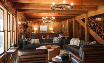 a cozy living room with wooden walls , a couch , and a coffee table , decorated with various pieces of furniture such as couches and chairs at Greenhorn Ranch