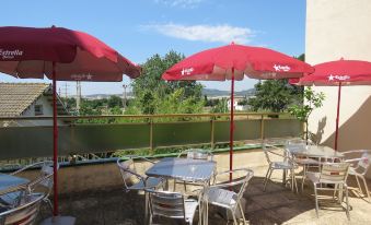 an outdoor patio with several red umbrellas , tables , and chairs set up for dining or relaxation at Royal Beach