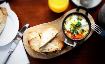 a wooden plate with a slice of bread and an egg dish is placed on a table at The White Horse Inn