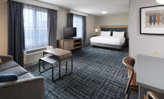 a hotel room with a king - sized bed , a flat - screen tv , a couch , and a dining table at Homewood Suites by Hilton Newburgh-Stewart Airport