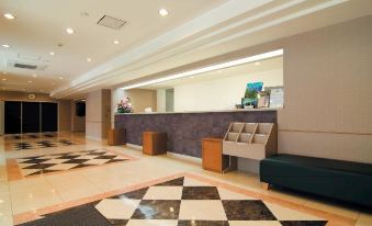 a modern hotel lobby with a check - in desk and a checkered floor , creating an inviting atmosphere at Ace Inn Matsumoto