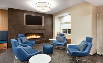 a modern living room with blue chairs , a fireplace , and a flat - screen tv mounted on the wall at Microtel Inn & Suites by Wyndham Warsaw