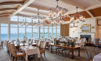 a large dining room with wooden tables and chairs , wine glasses , and chandeliers hanging from the ceiling at Wequassett Resort and Golf Club