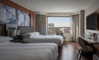 a hotel room with two beds , a desk , and a window offering a view of the city at Tysons Corner Marriott