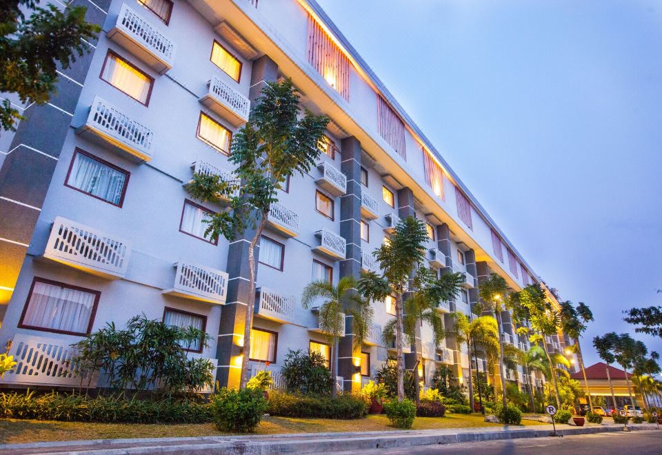 a modern apartment building with palm trees in front of it , under a clear blue sky at Lorin Dwangsa Solo Hotel