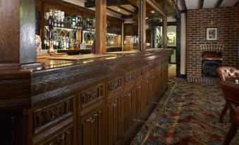 a wooden bar with a brick wall and carpeted floor , featuring numerous bottles of liquor at The Bull