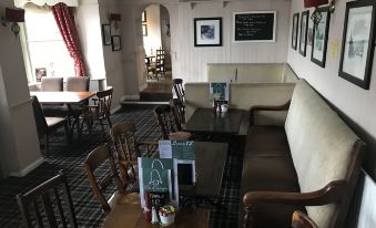 a dining area with tables , chairs , and a couch in a room with wooden flooring at Duke of Wellington