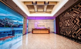 a modern , well - lit lobby with a reception desk and purple light fixtures , set against a white marble floor and large windows at favehotel Bitung