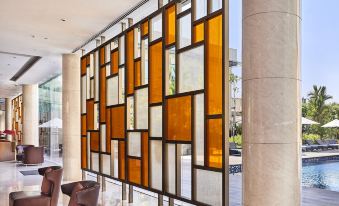 a modern glass partition with yellow and white geometric patterns is displayed in an open area at Courtyard Kochi Airport