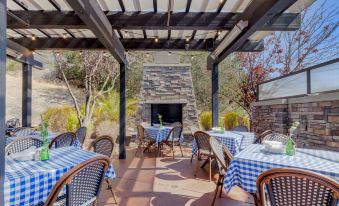 a restaurant with blue and white checkered tablecloths , chairs , and a fireplace in the background at Best Western Plus Novato Oaks Inn