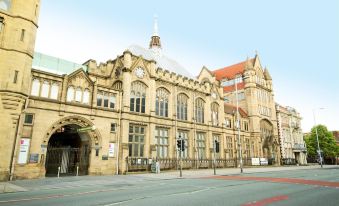 a large , old building with a dome and arches is shown in the middle of a street at Novotel Manchester West