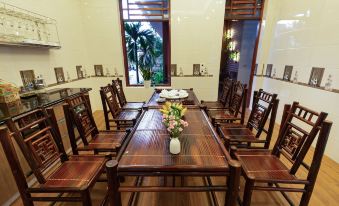a dining room with a wooden table surrounded by chairs , and a vase of flowers placed on the table at MH Cherish Homestay