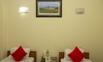a hotel room with two beds , a painting on the wall , and a table with a bottle of water at Hotel Marigold