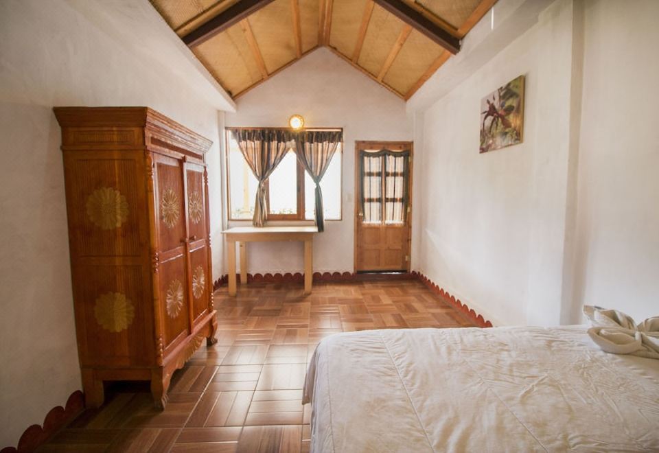 a room with a wooden arched ceiling , a wooden dresser , and a bed in the corner at Eco Hotel Uxlabil Atitlan