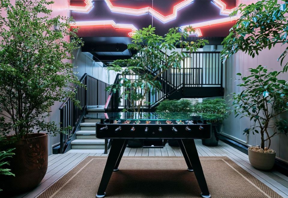 a black foosball table is set up in a room with potted plants and stairs at Nohga Hotel Akihabara Tokyo