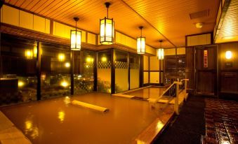 a dimly lit room with a long bathtub and several lights hanging from the ceiling at La Vista Hakodate Bay