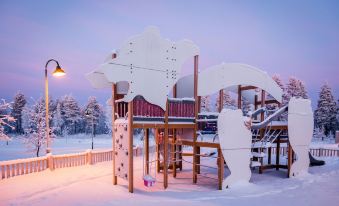 a wooden play structure with a slide and other play equipment is covered in snow at Ranua Resort Holiday Villas