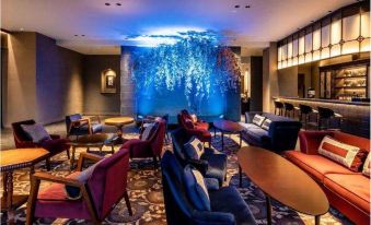 a modern lounge area with blue walls , circular tables , and red chairs , under a large blue painting at Kamisuwa Onsen Shinyu