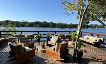 a wooden deck overlooking a body of water , with several chairs and a hammock placed on the deck at Juma Amazon Lodge