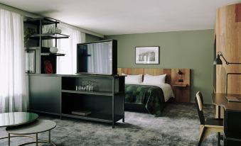 a modern hotel room with a large bed , a tv , and a desk , all set against a green wall at The Cambrian