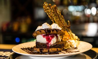 a plate of ice cream and waffles topped with whipped cream , chocolate sauce , and whipped cream at Wattle Grove Motel