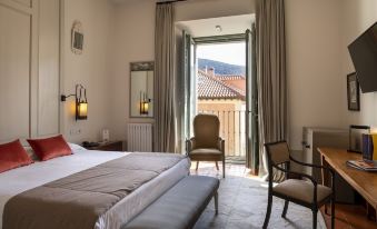 a hotel room with a comfortable bed , a chair , and a window overlooking a beautiful view at Parador de La Granja