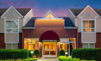 a brick building with a large arched entrance , surrounded by trees and bushes , during sunset at Sonesta ES Suites Nashville Brentwood