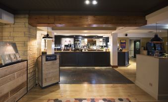 a modern bar with wooden floors , black and white checkered floor , and a wooden counter at Premier Inn Glasgow (Motherwell)