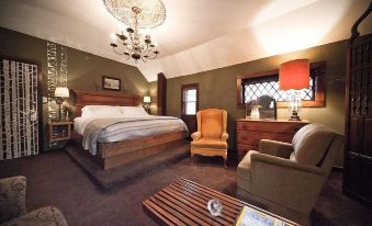 a large bed with a wooden headboard is in the middle of a room with chairs and a chandelier at The Inn
