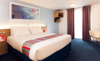 a large bed with white sheets and a red striped blanket is in a hotel room at Travelodge Hull South Cave